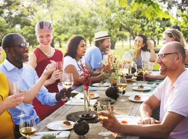 a group of people sitting at a dining table eating dinner outside