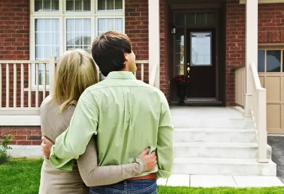 a couple embraces, looking at their home