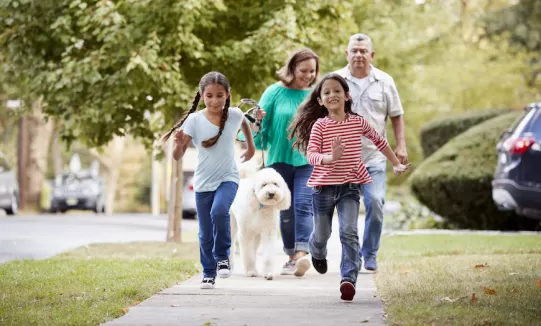 Family walking dog on the sidewalk.