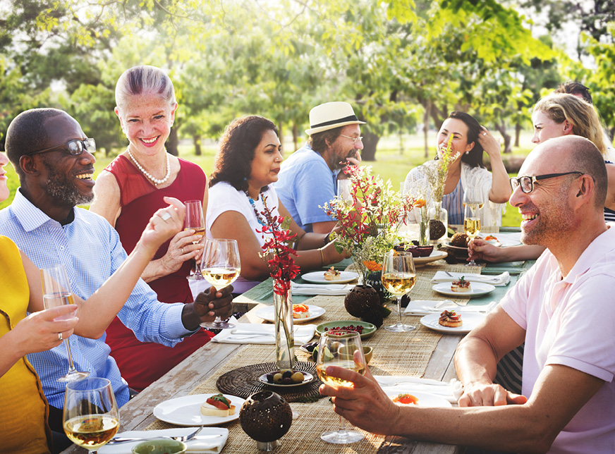 a group of people sitting at a dining table eating dinner outside